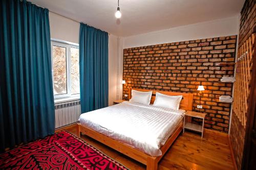 a bedroom with a bed and a brick wall at Hotel Good Night in Jalal-Abad