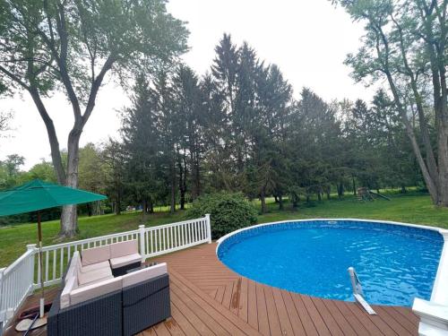 - une piscine sur une terrasse en bois avec un parasol dans l'établissement Pool, heated floors, king bed. Perfect getaway., à Warwick