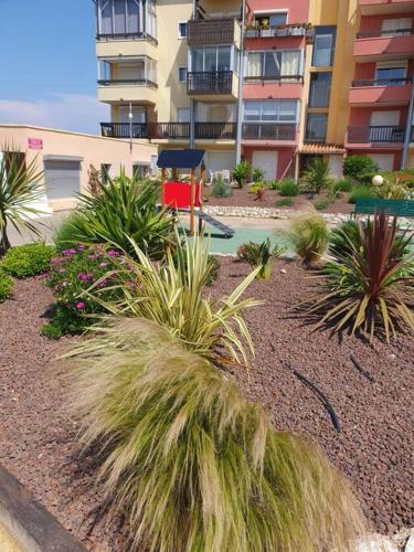 un jardin avec des plantes devant un bâtiment dans l'établissement Appartement, au Cap d'Agde