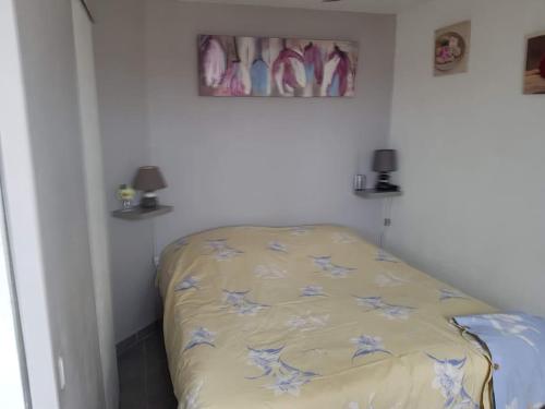 - une chambre avec un lit orné de fleurs bleues dans l'établissement Appartement, au Cap d'Agde