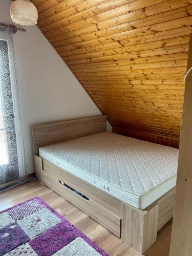 Cama en habitación con techo de madera en Extra House en Balatonvilágos