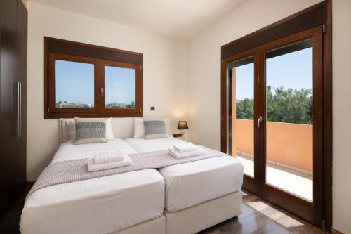 a bedroom with a large white bed and a window at Glamorous Villa Nefeli in Koskinou