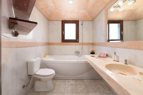 a bathroom with a tub and a toilet and a sink at Glamorous Villa Nefeli in Koskinou