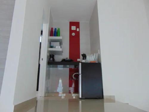 a kitchen with a black refrigerator and a red wall at NFT in Cancún