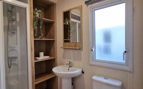 baño con lavabo y aseo y ventana en Cwtch, White Horse, Seal Bay Resort, en Selsey