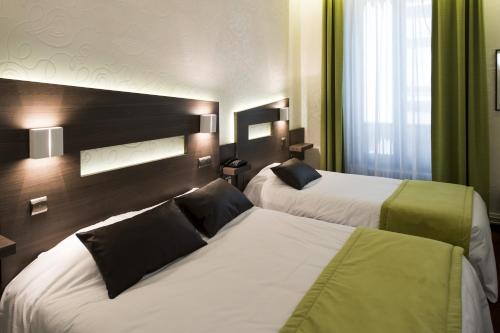 a hotel room with two beds and a window at La Résidence in Lyon