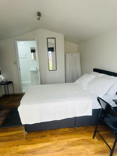 a bedroom with a large white bed and a chair at Comfortable Annex in Orsett
