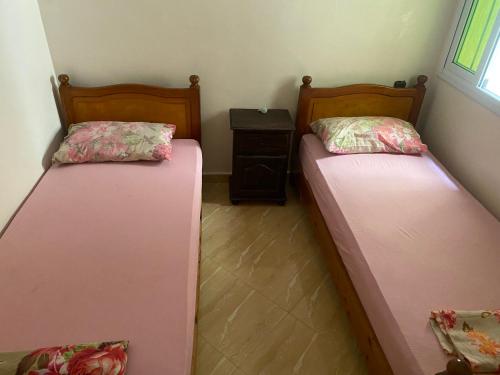 2 Einzelbetten in einem Zimmer mit einem Tisch in der Unterkunft Lotissment oum kaltoum 2 in Martil