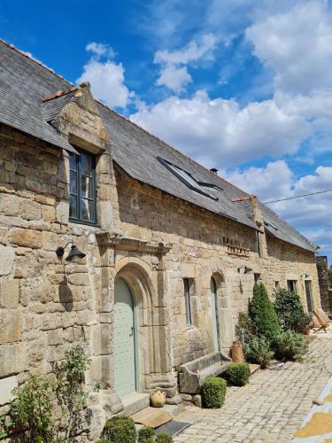 - un vieux bâtiment en pierre avec une porte verte dans l'établissement Villa Gloria, à Landaul