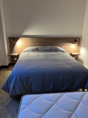 a bedroom with a large blue bed with two tables at Relais des Ardides in Bonnemazon