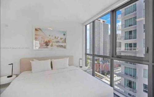 a bedroom with a white bed and a large window at Miami Downtown Comfy Condo-Hotels in a luxury modern building in Miami