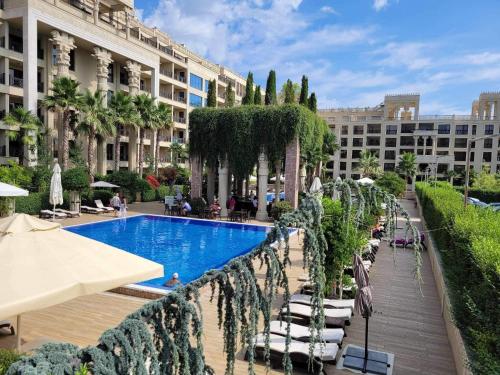 a swimming pool in a courtyard with chairs and a building at Argisht Luxury Apartment Golden Sands in Golden Sands