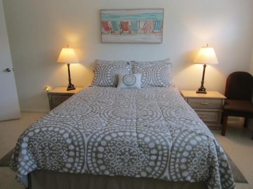 een slaapkamer met een bed met 2 lampen en 2 tafels bij Steps from the Gulf of Mexico in Holmes Beach
