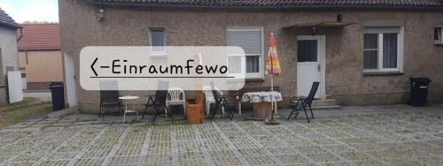 un panneau devant une maison avec des chaises et une table dans l'établissement Einraum-Ferienwohnung 46m2 Eisenhüttenstadt-Diehlo, à Eisenhüttenstadt