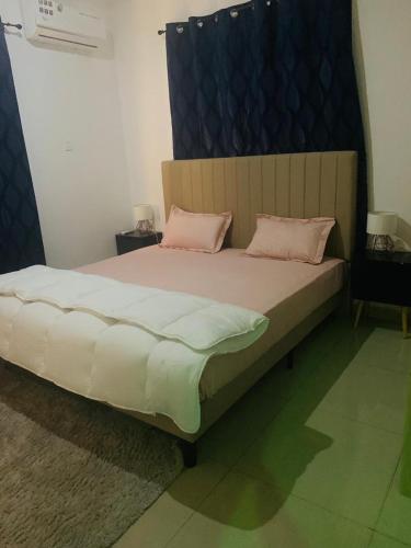 um quarto com uma cama grande e almofadas cor-de-rosa em Rahims 3 Bed Bungalow - Dalaba em Jarbang