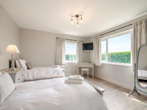 a white bedroom with two beds and a window at Manor Farm Cottage in Hornby