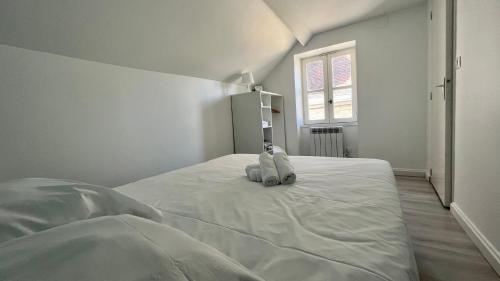 - une chambre blanche avec un lit avec un animal rembourré dans l'établissement Là-haut, à Nevers