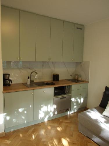 a kitchen with white cabinets and a sink and a couch at Prague 9 apartments in Prague
