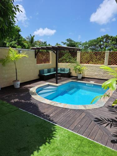 - une piscine dans un jardin avec une terrasse et une pergola dans l'établissement la casa mangue, au Diamant