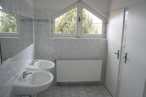 biała łazienka z 2 umywalkami i oknem w obiekcie TJ Lokomotiva Mariánské Lázně w Mariańskich Łaźniach