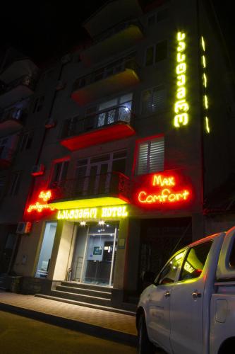 a white car parked in front of a building with neon signs at Hotel Max Comfort in Kutaisi