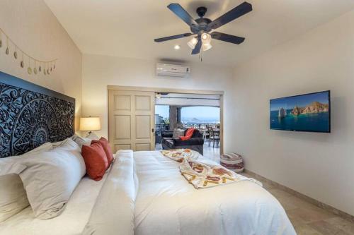 a bedroom with a large white bed with a ceiling fan at Ventanas Condo with Pool in Cabo San Lucas