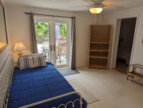 a bedroom with a blue bed and a sliding glass door at Steps from the Gulf of Mexico II in Holmes Beach