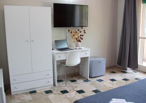 1 dormitorio con escritorio, ordenador portátil y TV en Mirage Place B&B en Catania