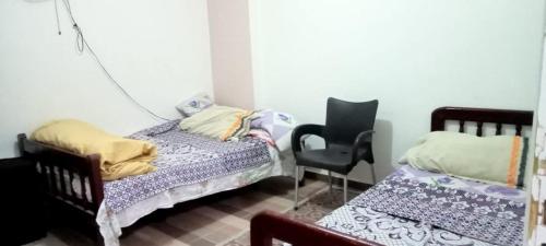 een slaapkamer met 2 aparte bedden en een stoel bij العجمي البيطاش بيانكى in Alexandrië