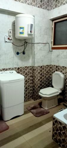 een badkamer met een wit toilet en een raam bij العجمي البيطاش بيانكى in Alexandrië