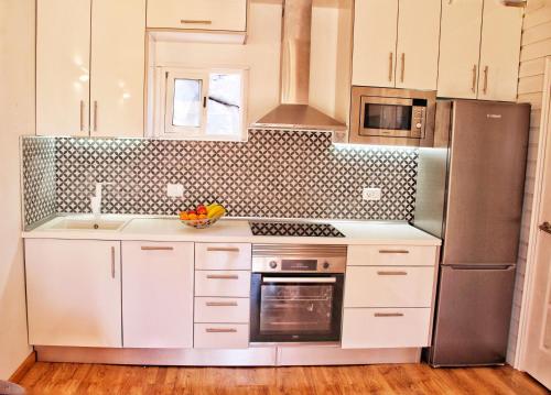 a kitchen with white cabinets and a stainless steel refrigerator at FINCA BEROLO 4 in Guía de Isora