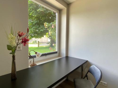 a room with a table and a vase of flowers on a window at Angenehmes Wohnen in Bad Bramstedt Appartement II in Bad Bramstedt