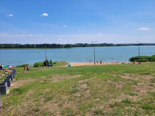 a group of people on a beach near a body of water at Domek Drewniany w Dolinie Symsarny in Lidzbark Warmiński