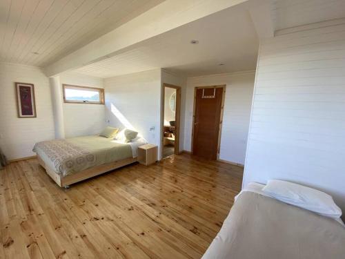 a bedroom with a bed and a wooden floor at Buchuvillas Surf House in Buchupureo
