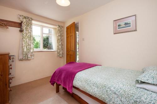 a bedroom with a bed and a window at Watermill Cottages - 18th Century converted Mill 10 mins from beach in Dartmouth