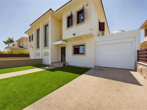 a house with a green lawn in front of it at Fabulous beach front house with pool in Larnaca