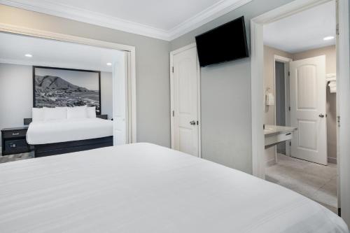 a white bedroom with a bed and a television at Aura Inn Monterey in Monterey