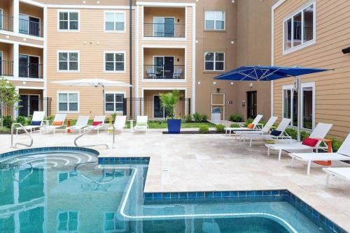 - une piscine avec des chaises et des parasols en face d'un bâtiment dans l'établissement Luxurious Apartment Home, à Creve Coeur
