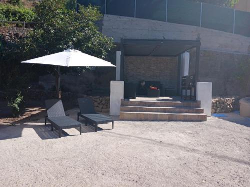a patio with two chairs and an umbrella at Casa Azul Mountain Retreat in Vega de San Mateo