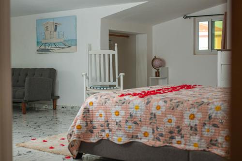 a bedroom with a bed with a blanket and a chair at Cidade Paradise Guesthouse in Cidade Velha