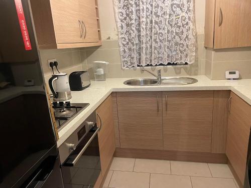 uma pequena cozinha com um lavatório e uma janela em Cozy Private Room in a Beautiful Accommodation close to Orpington em Foots Cray