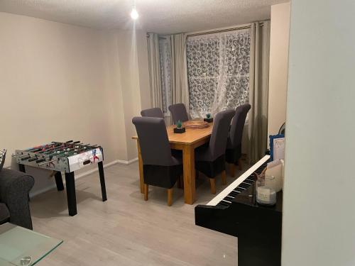 a room with a table and chairs and a piano at Cozy Private Room in a Beautiful Accommodation close to Orpington in Foots Cray
