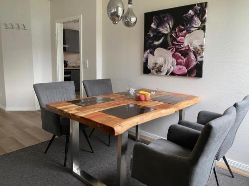 a dining room table with chairs and a painting on the wall at Angenehmes Wohnen in Bad Bramstedt Appartement II in Bad Bramstedt