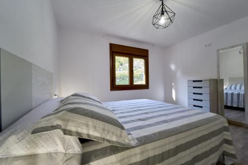Habitación blanca con cama y ventana en O Lar de Lola, en Mondariz