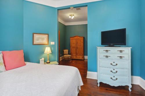 a bedroom with a bed and a tv on a blue wall at Maison Perrier Bed & Breakfast in New Orleans