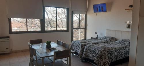 une pièce avec une table et un lit et une table et des chaises dans l'établissement Ruffus's Apple Cipolletti, à Cipolletti