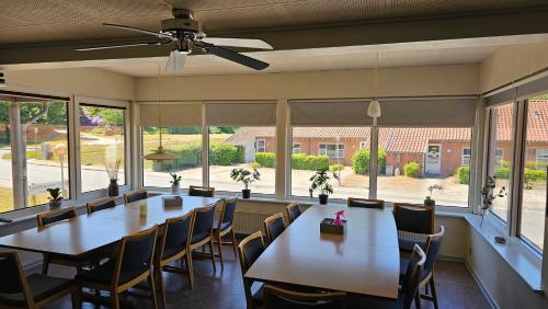 - une salle à manger avec des tables, des chaises et de grandes fenêtres dans l'établissement Gudum Park, à Lemvig