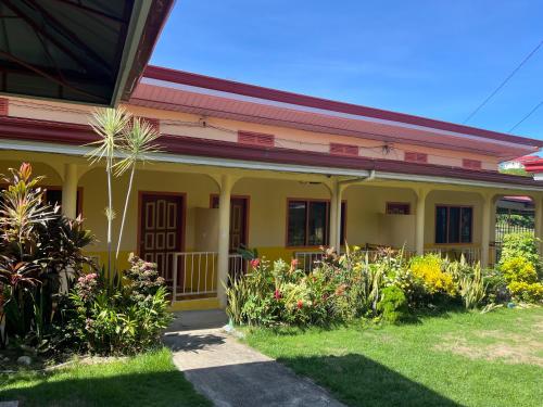 a yellow house with flowers in the yard at Uptown Guesthouse in Siquijor