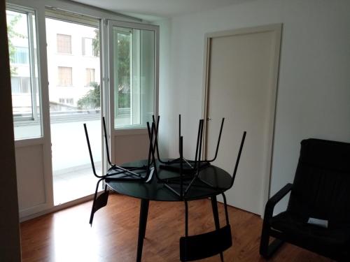 a black chair sitting in a room with a window at Appartement T4 des jardins in Chambéry