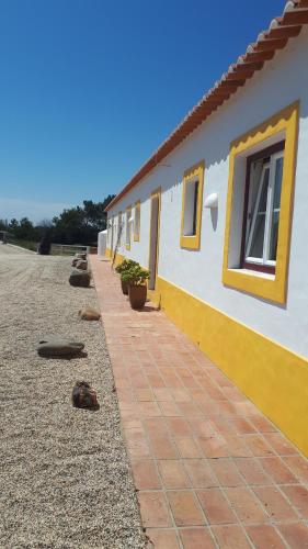 a house with yellow and white walls and a sidewalk at SeteQuintas in Zambujeira do Mar